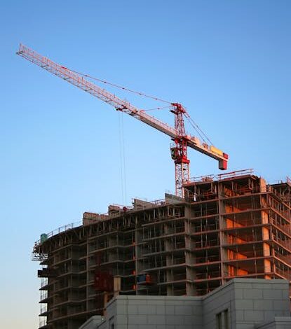 Tower crane on a high-rise building under construction at sunset, showcasing modern urban development.